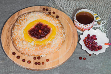 Cake of yeast dough with lemon cream and berries cranberries on a wooden plate with napkin on wooden retro table vintage top view