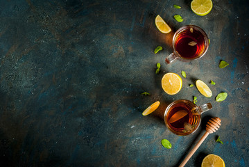 Black tea with lemon and mint on dark blue concrete stone background, copy space top view