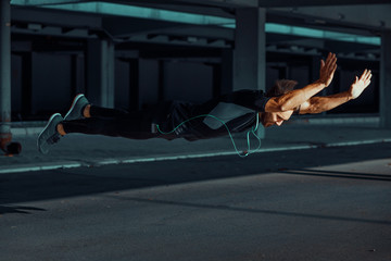 Young man doing push ups with jumps in the urban environment