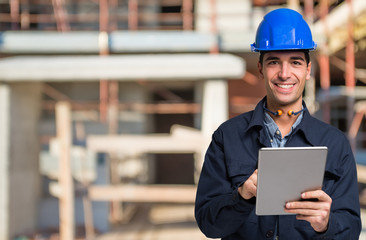 Worker using a tablet in front of a construction site