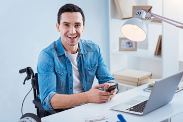 Express positivity. Young invalid man feeling happiness while looking at camera and going to work