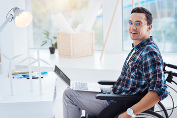 IT-man. Handsome brunette keeping smile on his face and turning head while sitting in semi position