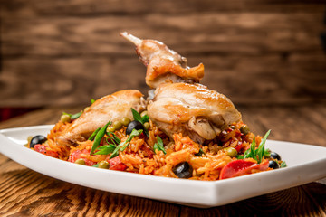 Plate with roasted rabbit leg and vegetable garnish.