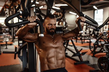 Fototapeta na wymiar Handsome man with big muscles working out in gym. Muscular bodybuilder doing exercises.