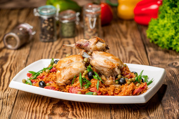 Plate with roasted rabbit leg and vegetable garnish.