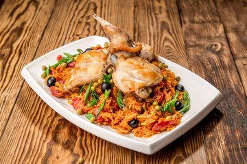 Plate with roasted rabbit leg and vegetable garnish.