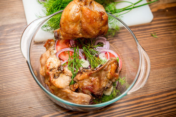 Roasted rabbit with herbs, tomato sauce and glass of wine on a plate.