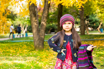 Autumn portrait of beautiful kazakh, asian child. Happy little girl with leaves in the park in fall.