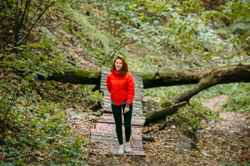 Naklejka na ściany i meble Cute sporty girl in red jacket is walking in forest. Autumn. Artwork