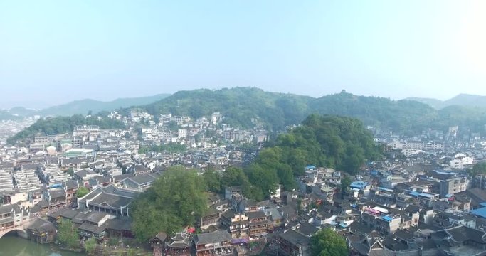 Top view or aerial shot of famous ancient town in Fenghuang County, China. Flying over Green River, hills and houses of the village. Travel,destination and world heritage concept.