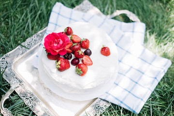 Delicious rustic hand made white fluffy cake with fresh strawberries and cherries on the top.