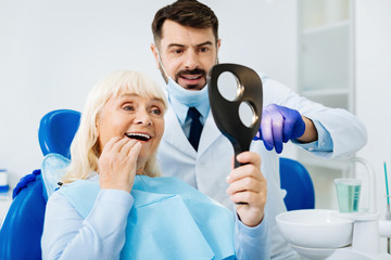 Perfect work. Positive patient being satisfied while looking in the dental mirror and expressing...