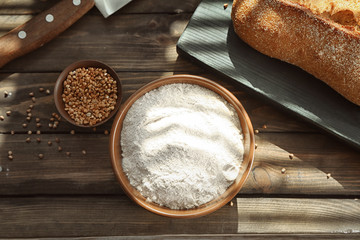 Fototapeta na wymiar Composition with buckwheat flour and fresh bread on wooden table