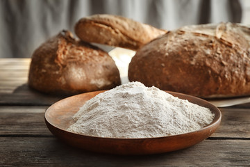 Plate with buckwheat flour on wooden table