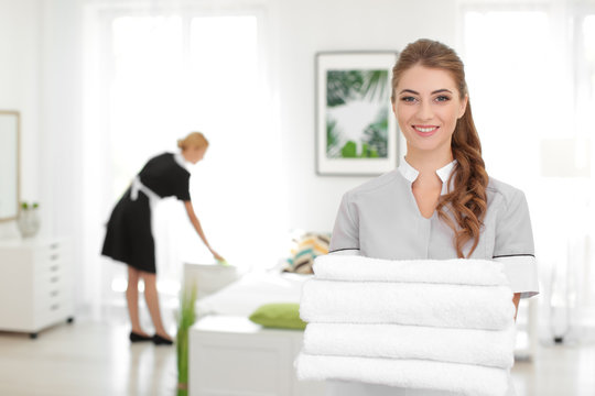 Beautiful chambermaid with towels in room