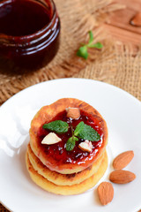Obraz na płótnie Canvas Cottage cheese cakes. Fried cottage cheese cakes with berry jam and almonds on a white plate. Traditional ukrainian syrniki recipe. Vertical photo