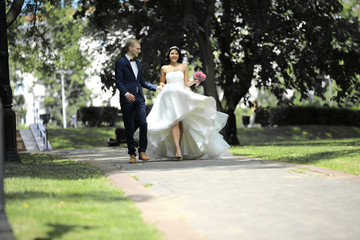 day of the wedding the beautiful bride and groom walk through the park