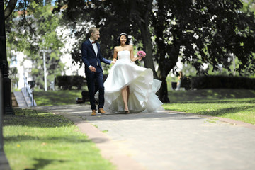 Fototapeta premium day of the wedding the beautiful bride and groom walk through the park