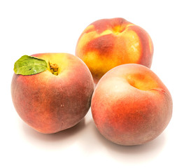 Fototapeta na wymiar Three whole ripe peaches, one with green leaf, isolated on white background.