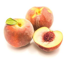 Two whole peaches and one sliced half with a stone isolated on white background.