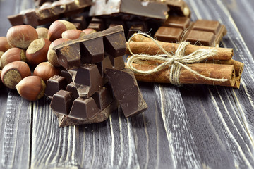Chocolate pieces with nuts on dark wooden background. Selective focus. Rustic style.