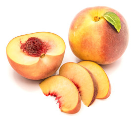 Group of peaches, whole with a green leaf, one half with a stone, isolated on white background.
