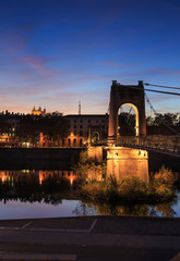 Naklejka premium Illuminated footbridge Passerelle du College over the Rhone river in Lyon during dusk.