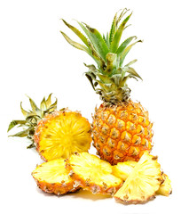 Fresh round pineapple slices and one whole pineapple with green leaves isolated on white background.