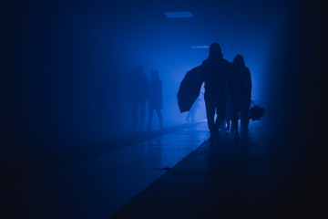 silhouette of people walking in a tunnel in smoke against a background of bright light