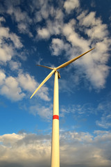 Wind turbines in landscape against blue sky and clouds