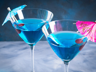 Blue cocktail drink in martini glass with umbrella and cherry