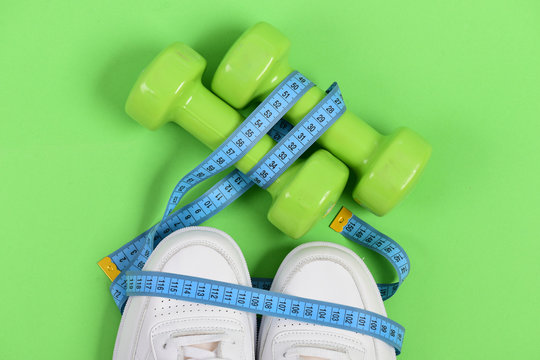 Centimeter in cyan blue color on white trainers and dumbbells