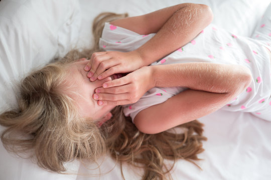 Young girl with long hair laying on her back with her eyes closed and waking up