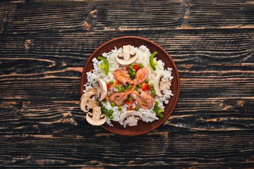 Risotto with shrimp and vegetables. Seafood. Asian cuisine. On a wooden texture background. Top view. Free space.