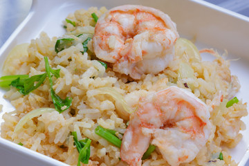 Fried rice with shrimp on the white dish on wooden table from top view