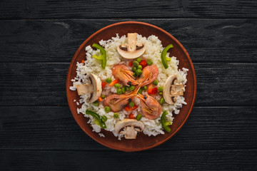 Risotto with shrimp and vegetables. Seafood. Asian cuisine. On a wooden texture background. Top view. Free space.