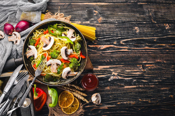 Noodles with vegetables in a frying pan. Asian Cuisine Pasta. Top view. Free space. On a wooden background.;