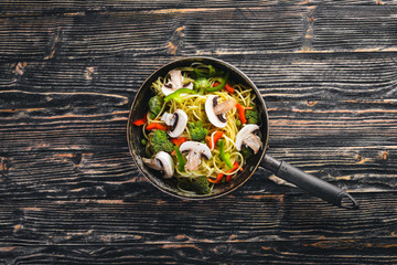 Noodles with vegetables in a frying pan. Asian Cuisine Pasta. Top view. Free space. On a wooden background.;