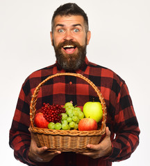 Man with beard holds fruit basket with fruit, white background