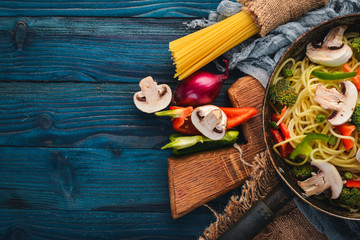 Noodles with vegetables in a frying pan. Asian Cuisine Pasta. Top view. Free space. On a wooden background.;