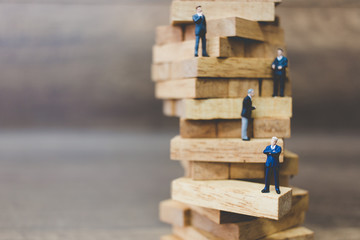 Miniature people: Businessman standing on wood block