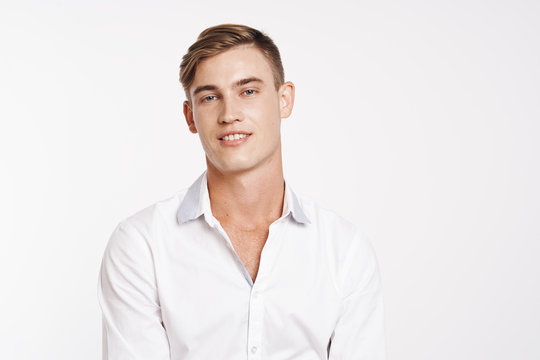 young man in a white shirt smiles into the camera