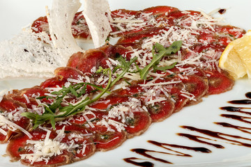 Beef carpaccio with arugula and lemon, parmesan and sauce.