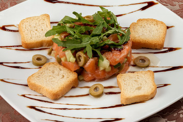 Salmon tartar with avocado, cucumber, olives and arugula.