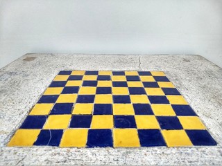 The mosaic blue and yellow chess board built in the mable table in perspective view with white wall background.