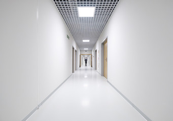 Business man back view at long white empty corridor interior