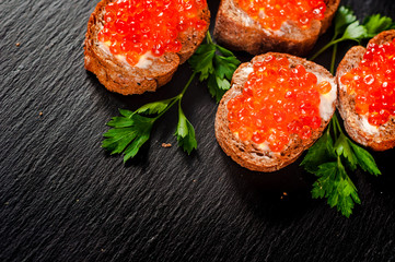 Red caviar on slate background.