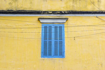 Fototapeta na wymiar Blue window on yellow wall in Hoi An