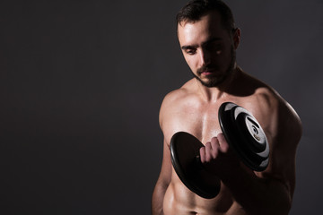 Obraz na płótnie Canvas Muscular bodybuilder guy doing exercises with dumbbell