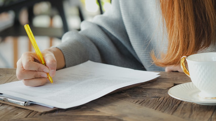 Business woman hand holding pen writing on papers at seminar or signing contract making a deal